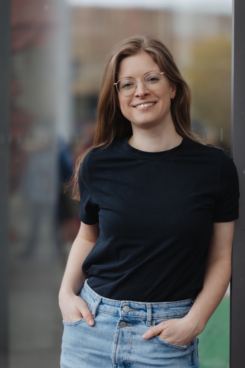 Porträt von Verena Gerardy, an eine Glasfront gelehnt